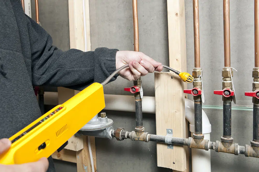 Technician uses gas detector on pipe fittings — Lake Gaston Area gas line inspection service