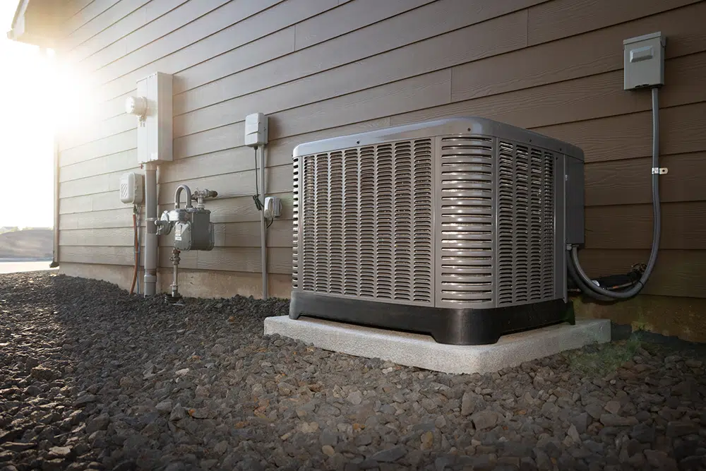 Central AC condenser unit beside a home at golden hour — AC installation service Lake Gaston Area