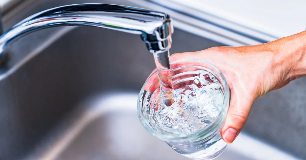lear water filling a glass from a kitchen faucet — whole-home water filtration near Lake Gaston Area